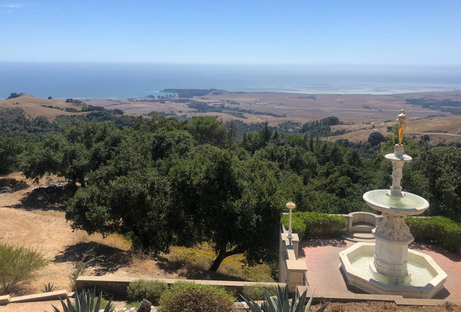 A fountain, wooded hills and the Pacific coast seen from Hearst Castle